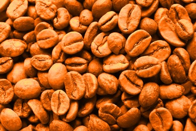 Coffee beans as background, top view. Toned in orange