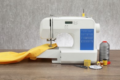 Photo of Sewing machine with fabric and craft accessories on wooden table