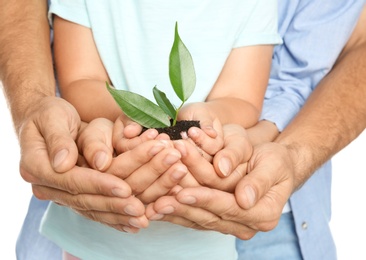 Family holding soil with green plant in hands on white background