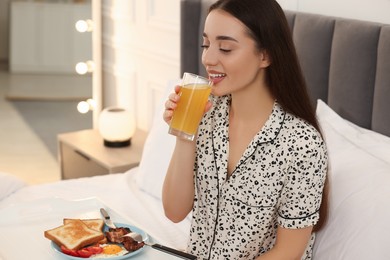 Photo of Happy young woman having breakfast on bed at home