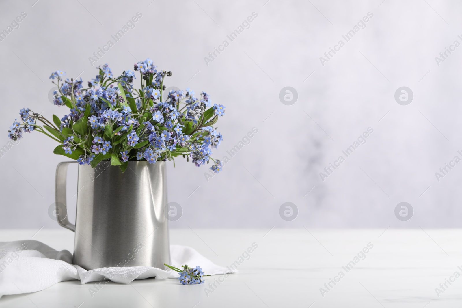 Photo of Beautiful forget-me-not flowers on white table, closeup. Space for text