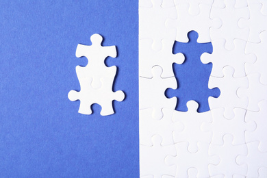 Photo of Blank white puzzle with separated pieces on blue background, flat lay