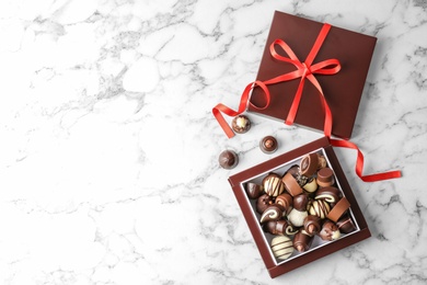 Box with different tasty chocolate candies on table, top view