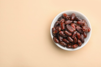 Photo of Bowl with sweet dried date fruits on color background, top view. Space for text