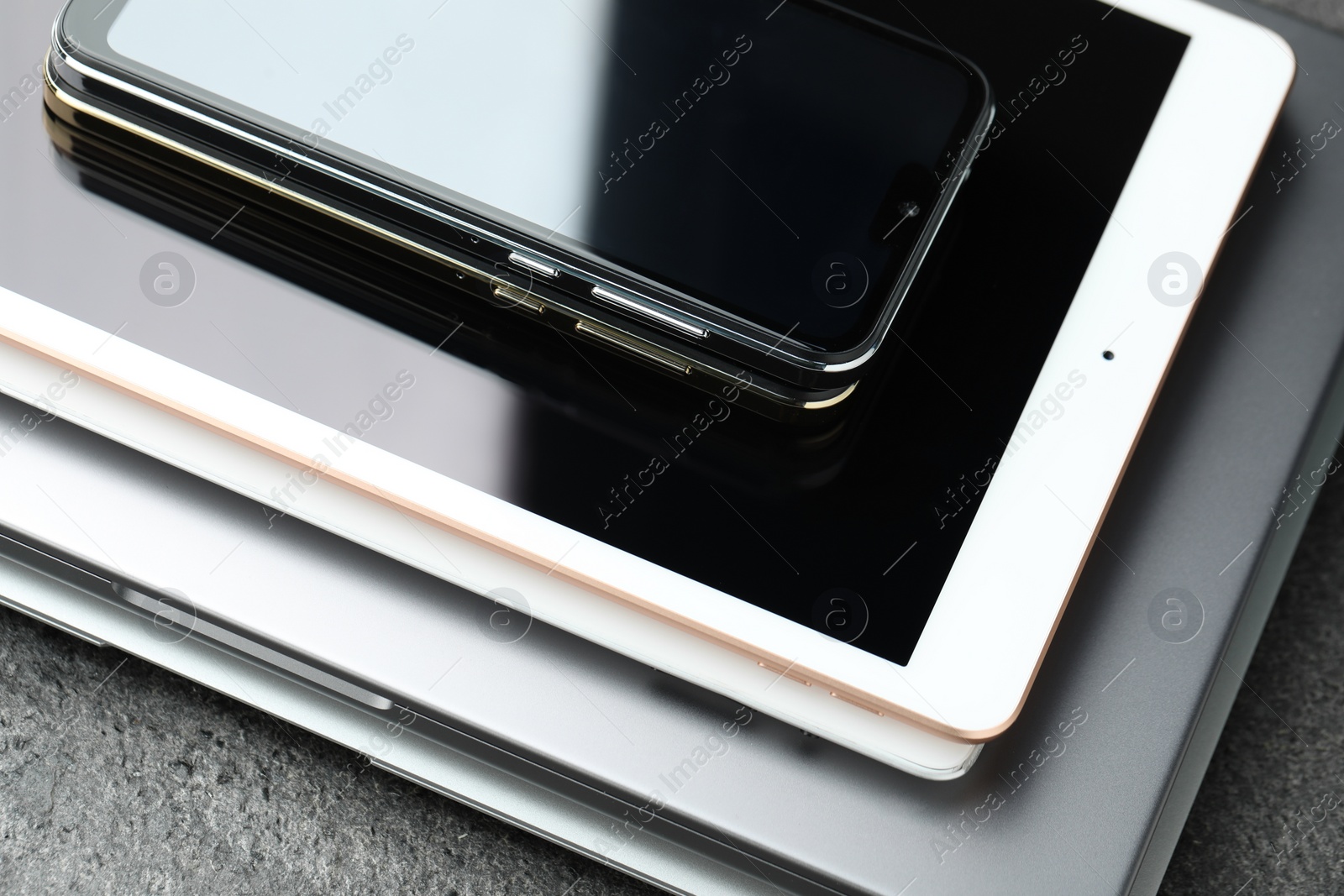 Photo of Stack of electronic devices on grey table, closeup