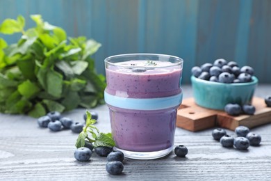 Photo of Glass of freshly made blueberry smoothie on grey wooden table