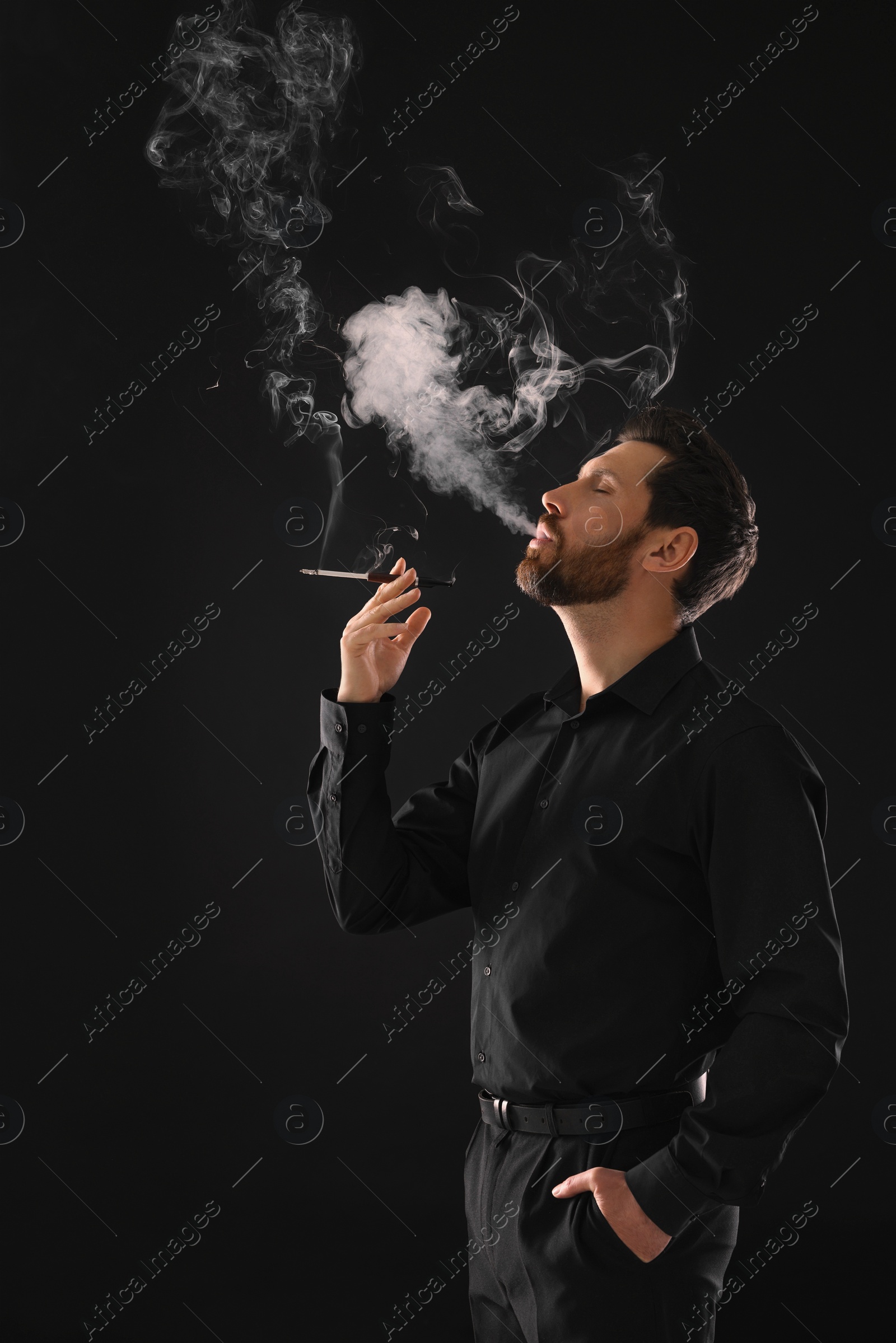 Photo of Man using cigarette holder for smoking on black background, space for text