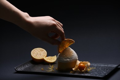 Food stylist creating beautiful composition with delicious dessert on black background, closeup