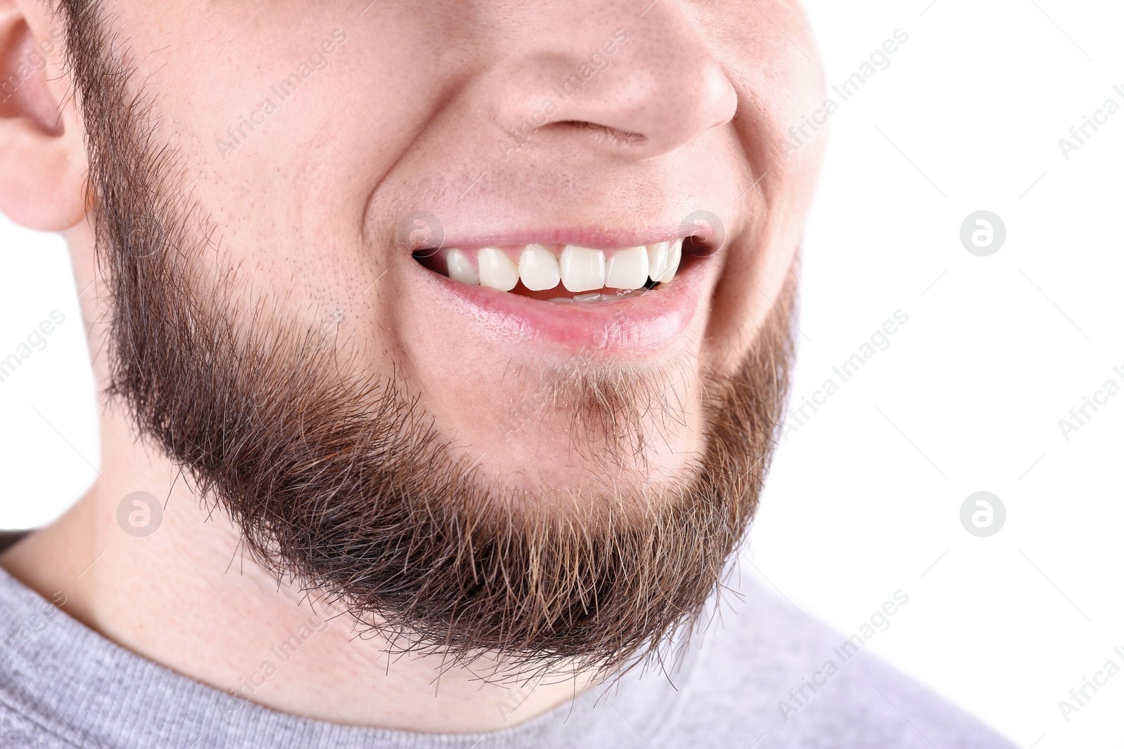 Photo of Young man with healthy teeth smiling on white background, closeup