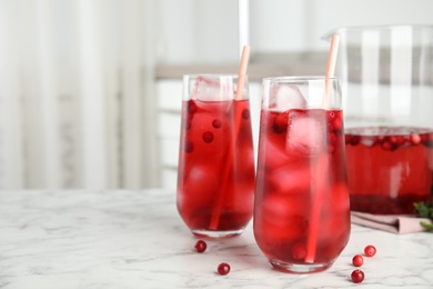 Photo of Tasty refreshing cranberry cocktail on white marble table indoors. Space for text