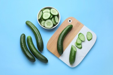 Photo of Fresh ripe cucumbers on light blue background, flat lay
