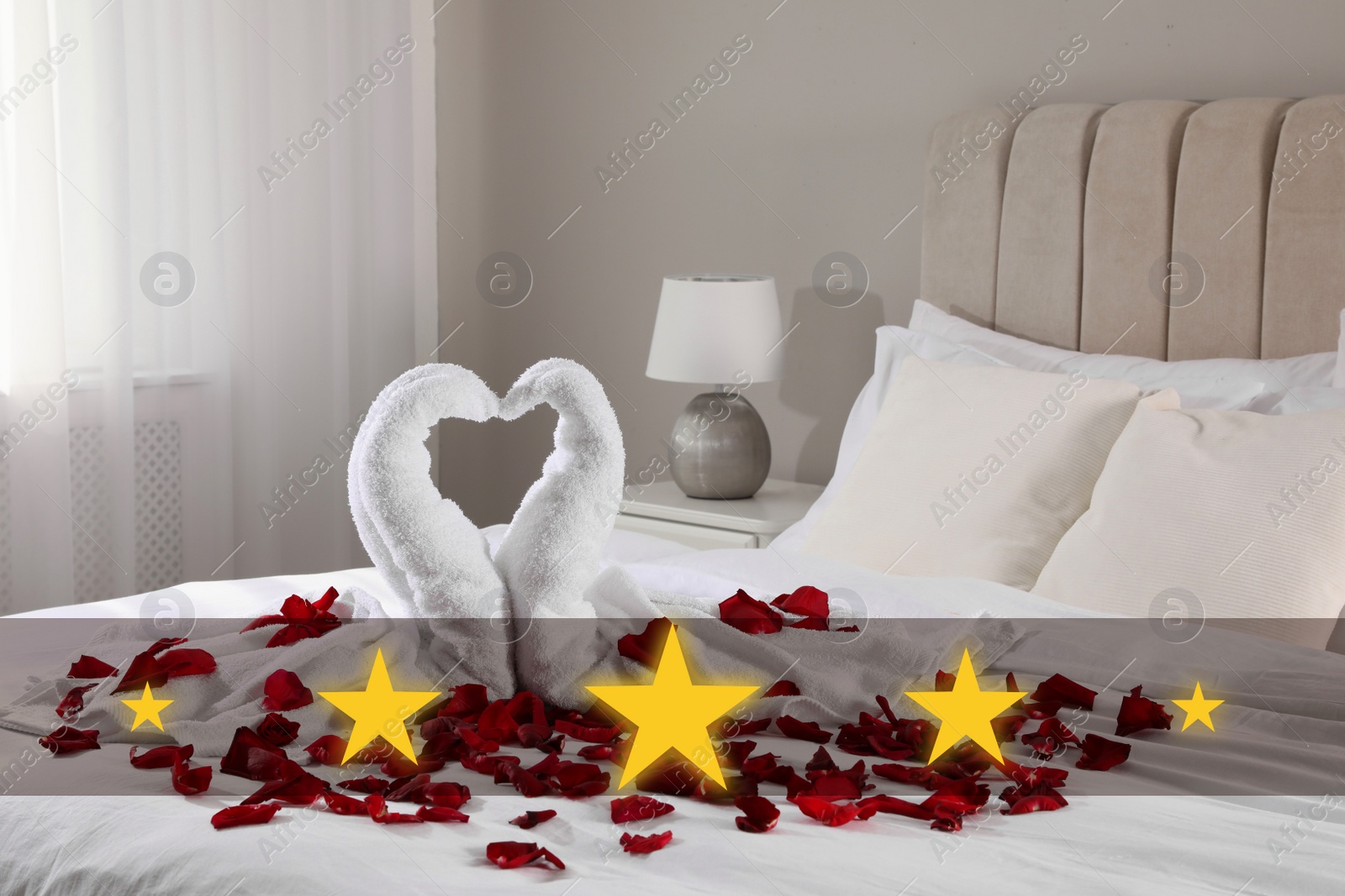 Image of Beautiful swans made of towels and red rose petals on bed in five star hotel room, closeup