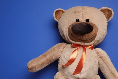 Cute teddy bear on blue background, top view. Space for text