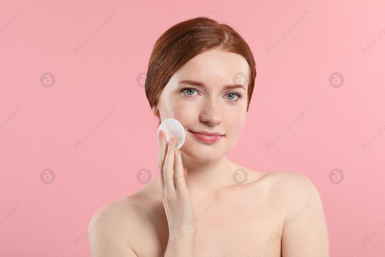 Photo of Beautiful woman with freckles wiping face on pink background