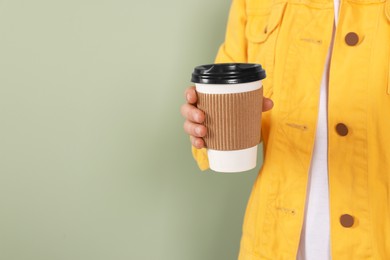 Photo of Woman holding takeaway cup with drink on pale green background, closeup view and space for text. Coffee to go