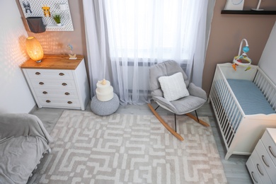 Cozy baby room interior with crib and rocking chair