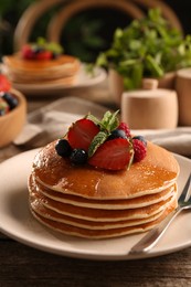 Tasty pancakes with fresh berries and mint on wooden table, closeup