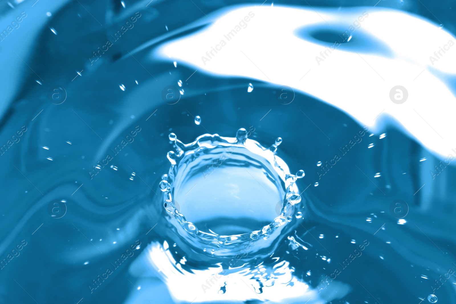 Photo of Splash of clear water with drop on blue background, closeup