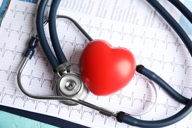 Photo of Stethoscope, red heart and cardiogram on table. Cardiology concept