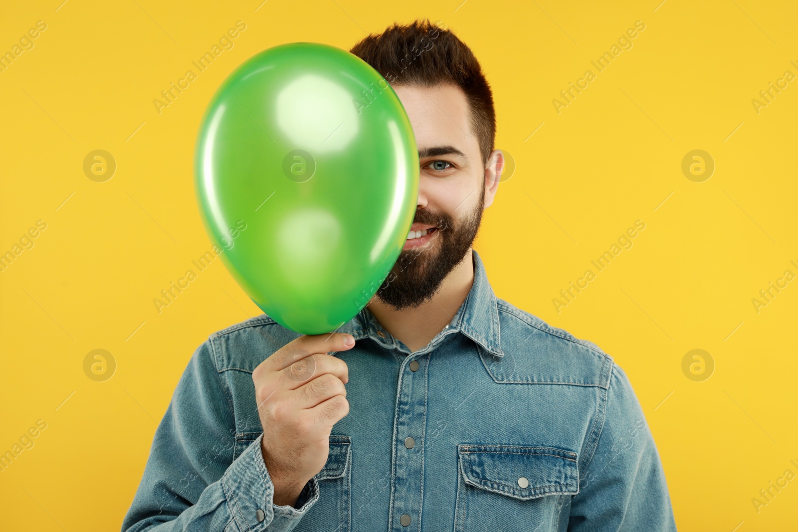 Photo of Happy man with bright balloon on yellow background