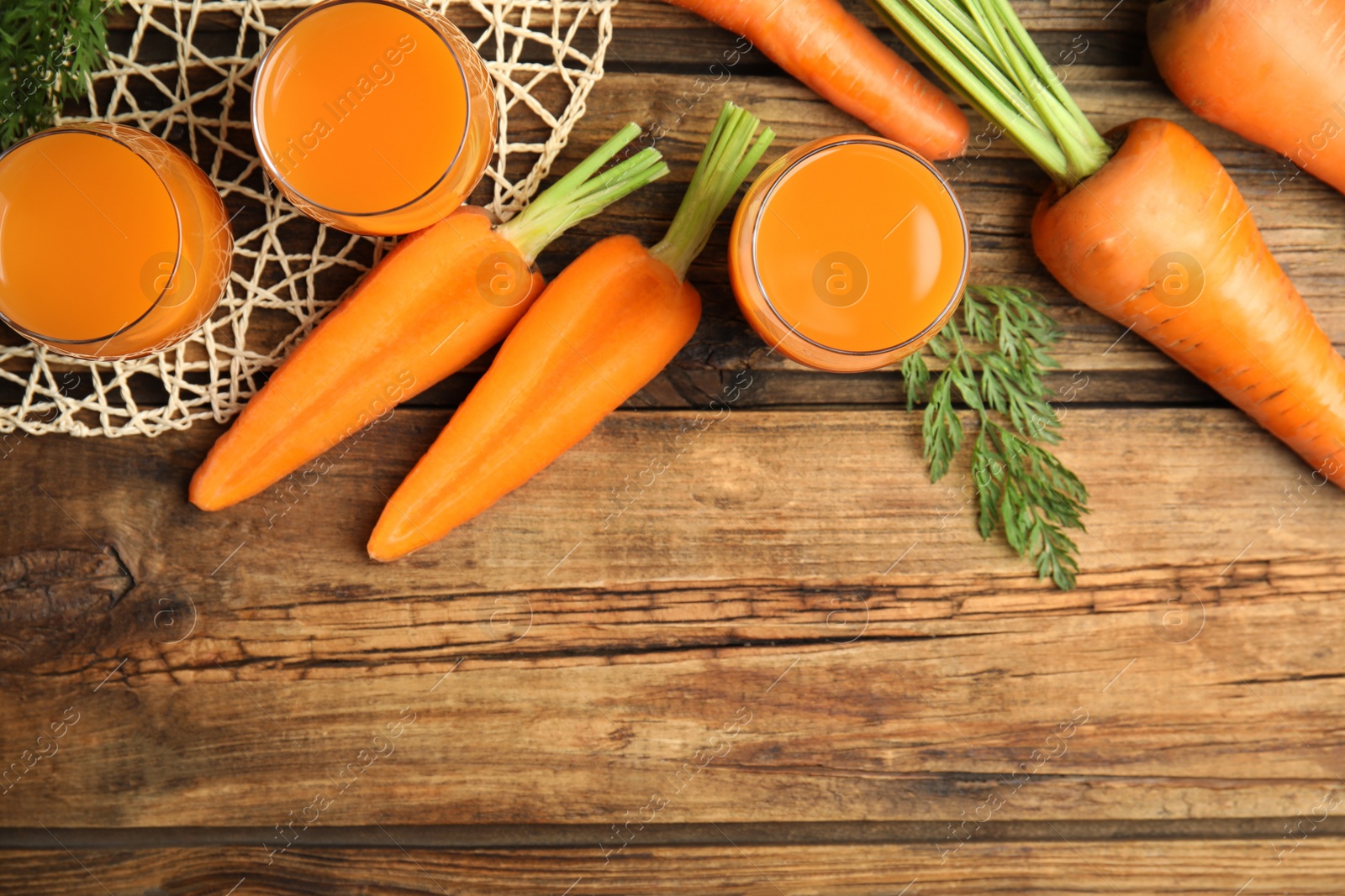 Photo of Freshly made carrot juice on wooden table, flat lay. Space for text