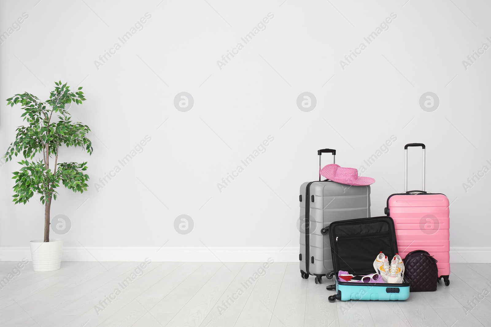 Photo of Modern suitcases on floor near light wall. Space for text