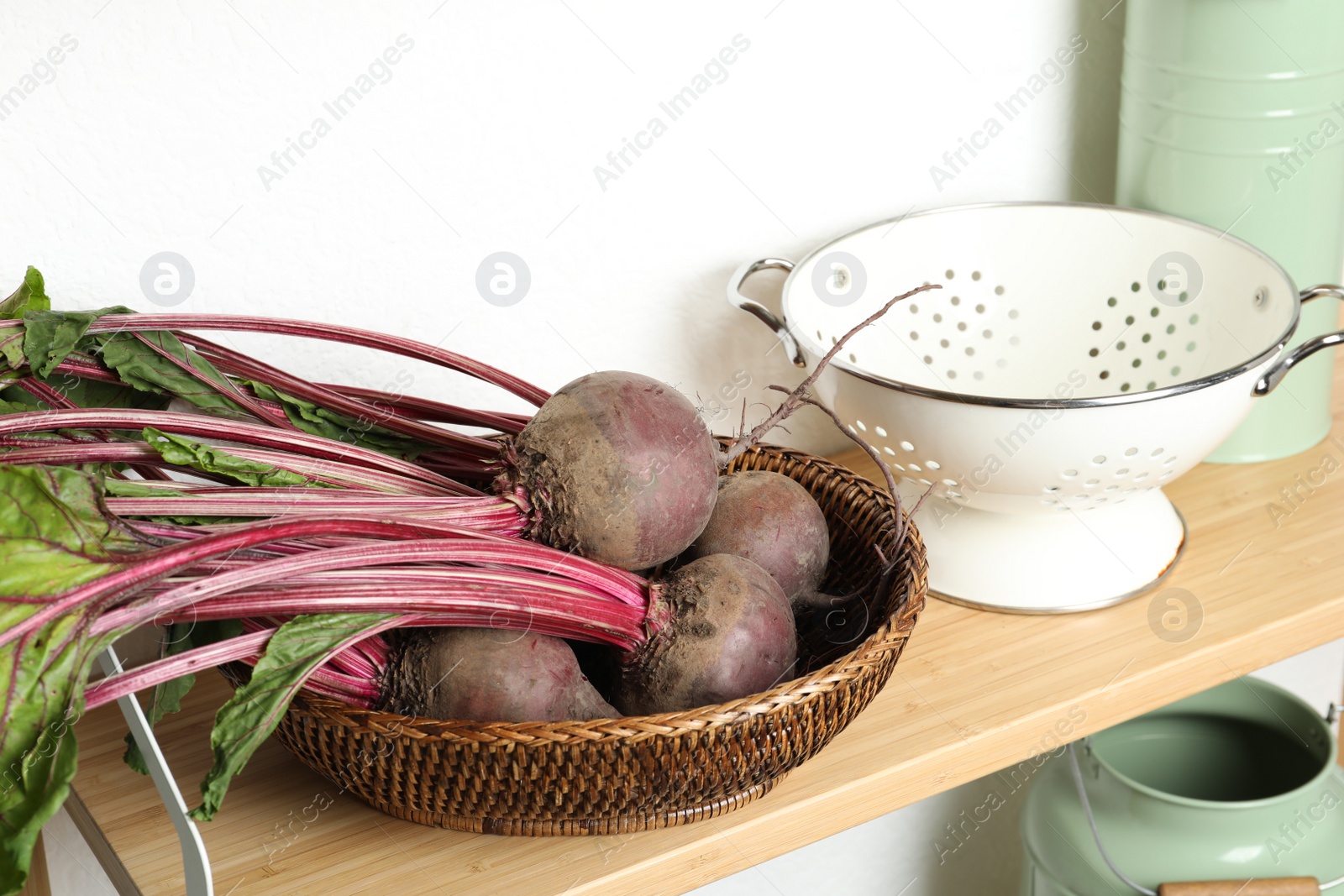 Photo of Raw ripe beets in wicker bowl on shelf indoors