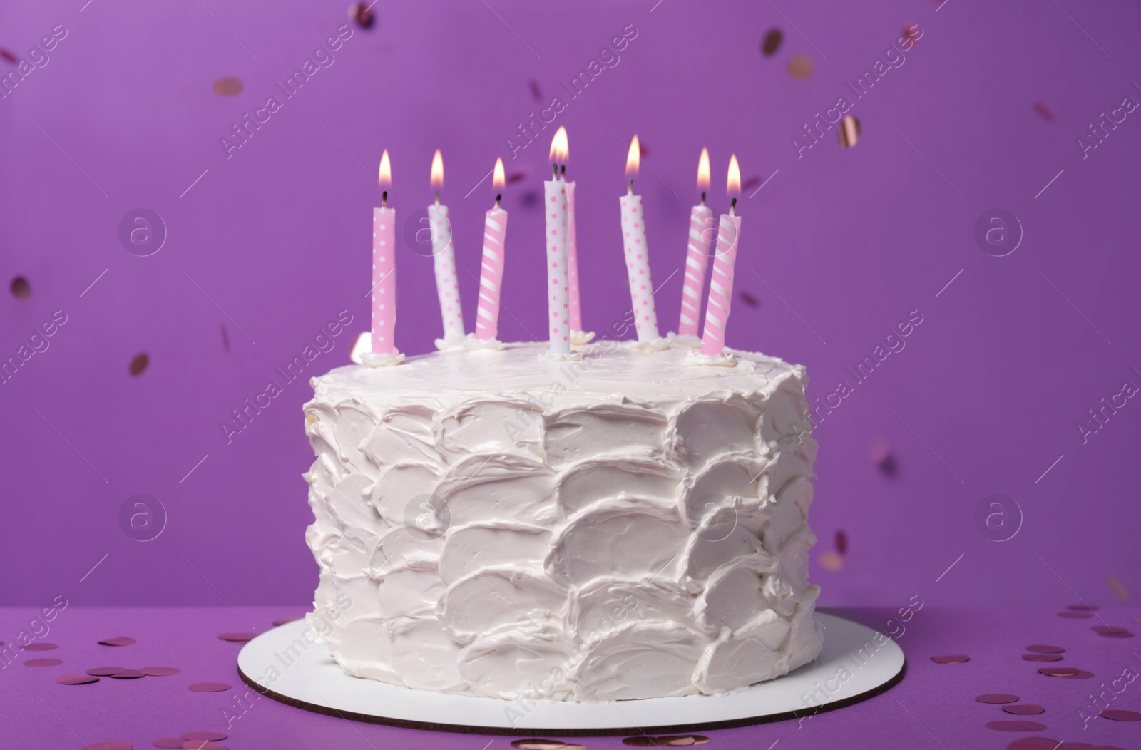 Photo of Delicious cake with cream and burning candles on purple background