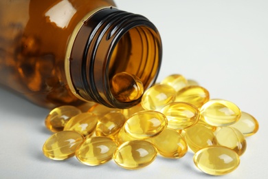 Bottle with cod liver oil pills on table, closeup