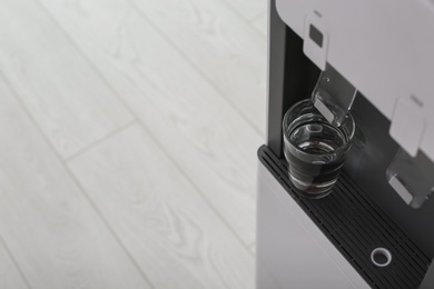 Modern water cooler with glass indoors, closeup. Space for text