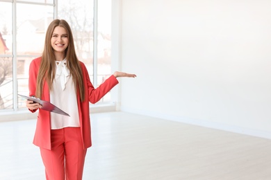 Photo of Beautiful real estate agent with clipboard indoors