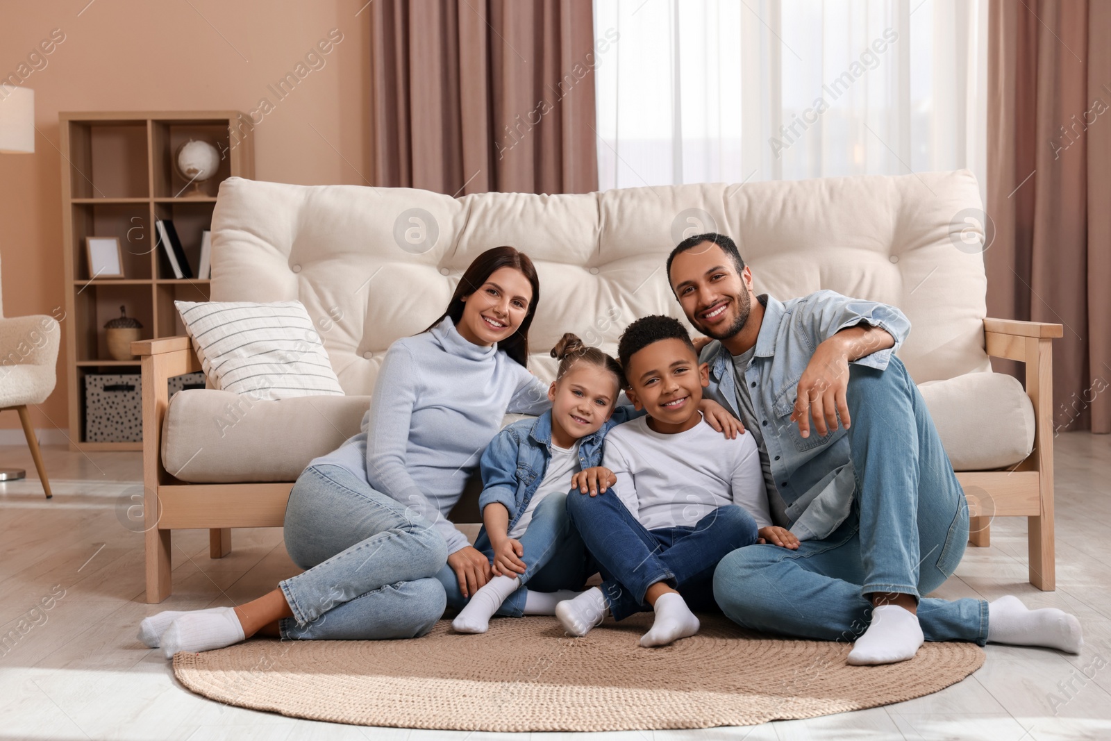 Photo of Happy international family with children near sofa at home