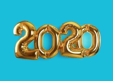 Photo of Golden balloons for party decoration on turquoise background. 2020 New Year celebration