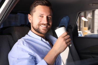 Photo of Coffee to go. Happy man with paper cup of drink in car