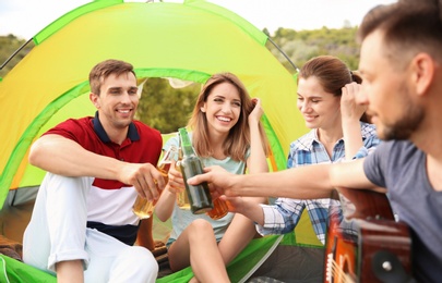 Photo of Group of young people with beer in wilderness. Camping season