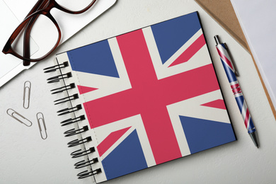 Image of Stylish notebook and pen on white table, flat lay. Learning English
