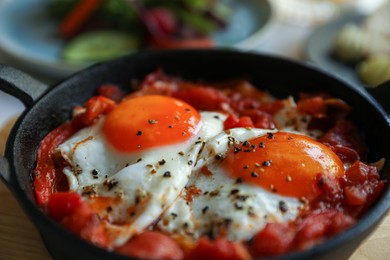 Tasty Shakshouka served in pan on table, closeup