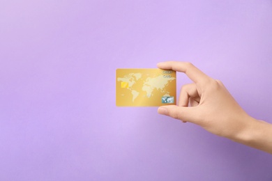 Woman holding credit card on color background