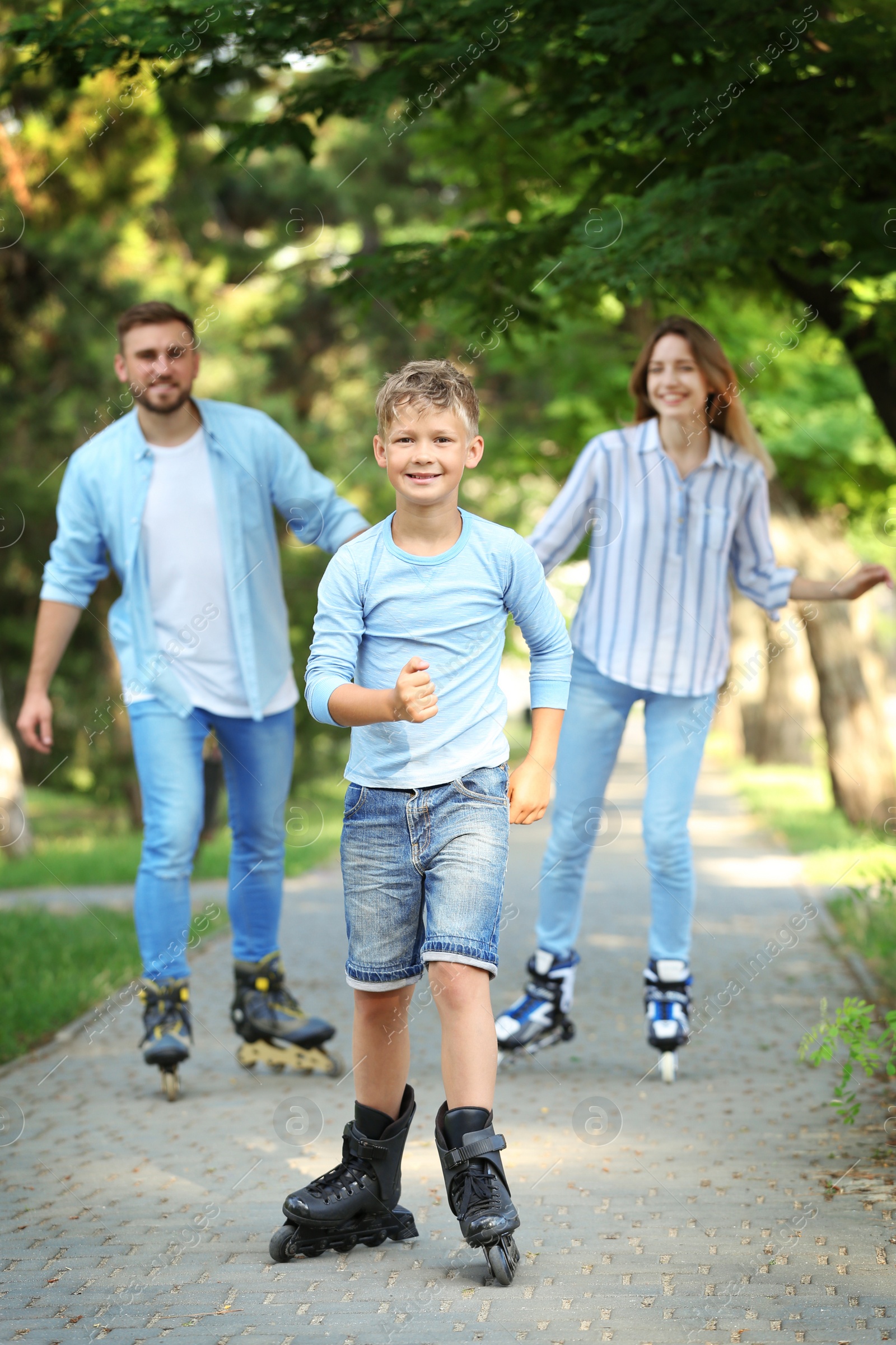 Photo of Young happy family roller skating in summer park