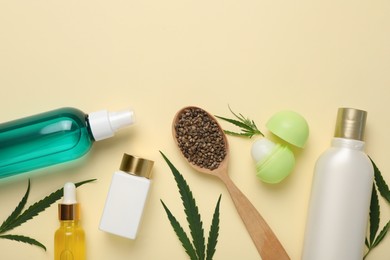 Different hemp cosmetics, green leaves and seeds on beige background, flat lay. Space for text