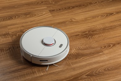 Photo of Robotic vacuum cleaner on wooden floor, space for text