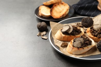 Delicious bruschettas with truffle sauce on grey table. Space for text