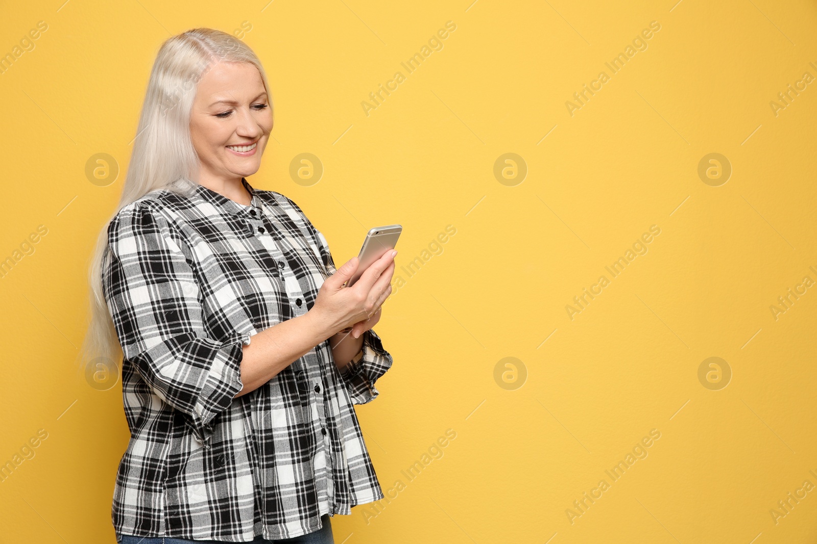 Photo of Mature woman using mobile phone on color background