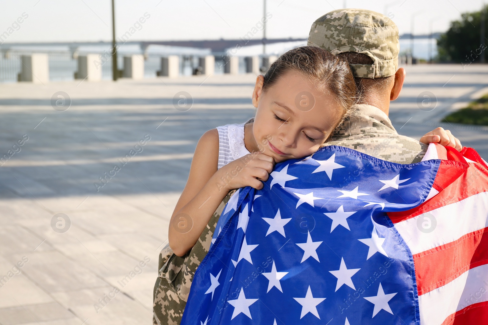 Photo of Soldier with flag of USA and his little daughter hugging outdoors, space for text