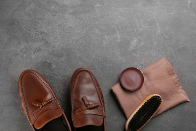 Photo of Flat lay composition with shoe care accessories and footwear on grey stone background. Space for text