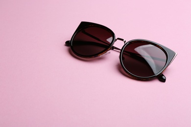 Stylish sunglasses on pink background, space for text. Fashionable accessory