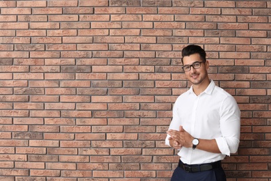 Portrait of handsome young man and space for text on brick wall background
