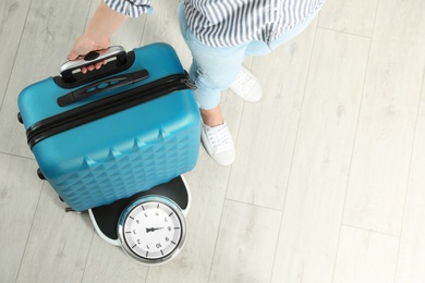 Photo of Woman weighing suitcase indoors, top view. Space for text