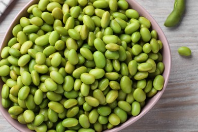 Photo of Bowl of delicious edamame beans on light wooden table, closeup. Top view