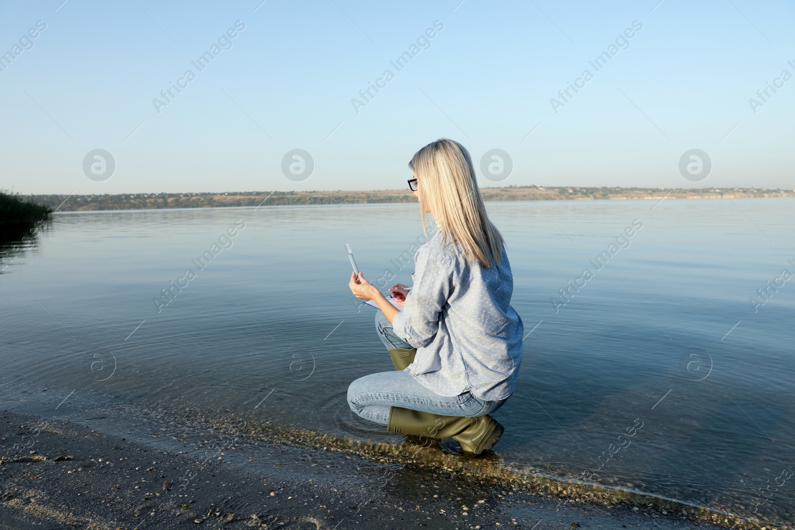 Photo of Scientist with clipboard and sample taken from river